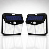 Two black solar-powered outdoor light fixtures with blue solar panels and white LED light grids, shown side by side on a reflective white surface against a light gray background.