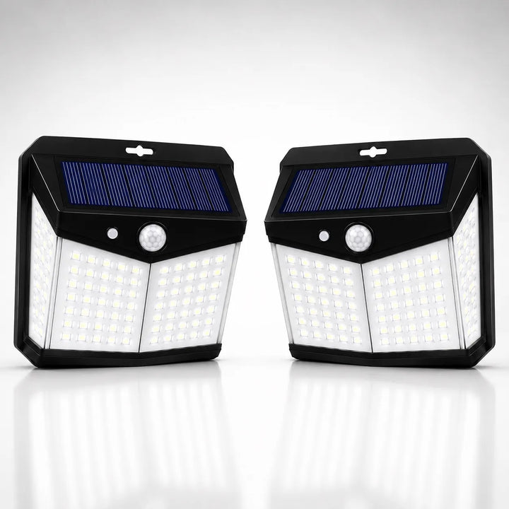 Two black solar-powered outdoor light fixtures with blue solar panels and white LED light grids, shown side by side on a reflective white surface against a light gray background.