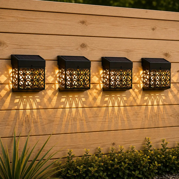 Four black outdoor wall lights on a wooden wall with plants in the foreground